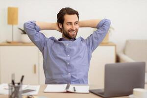 Carefree Businessman Relaxing Sitting Holding Hands Behind Head At Workplace In Office. Cheerful Entrepreneur Resting Sitting At Laptop. Successful Business Career Concept photo