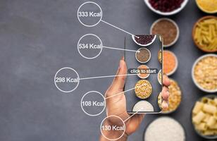Losing weight easily. Cellphone counting amount of calories on background with cereals and pasta photo