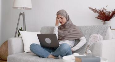 Concept of malware and computer virus. Stressful muslim lady screaming on damaged laptop caused by bug, having connection problems working online at home photo