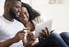 Cheerful Black Spouses Shopping Online Using Digital Tablet At Home, Entering Credit Card Security Code photo