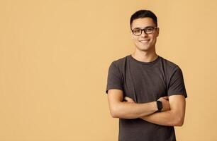 Nerd student blogger on self-isolation during lockdown. Smiling surprised young man model in casual, glasses and smart watch with crossed arms look at camera, isolated on light background, studio shot photo