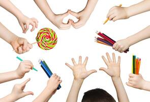 Set of child hands holding items. Lollipop, pencils and showing heart, symbols in various hadns. Isolated at white background photo
