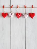 Valentine background with sewed pillow diy handmade hearts row border on red clothespins at rustic white wood planks. Happy lovers day card mockup, copy space, vertical photo