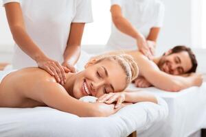 Relaxed Couple Receiving Back Massage Treatment Enjoying Lying On Beds With Eyes Closed At A Spa Resort Indoors On Weekend Day. Relaxation, Beauty And Wellness Procedure For Spouses. Selective focus photo