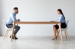 Interview, Business Meeting Concept. Profile side view of two serious people in formalwear sitting in front of each other at long desk in the office while discussing something, hr hiring staff photo