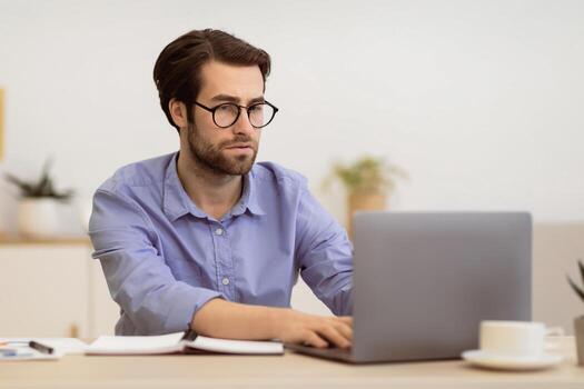 Focused Businessman Frowning Working On Laptop Having Difficult Task At Workplace In Modern Office. Serious Entrepreneur Typing On Computer Indoors, Having Issue With Internet Connection photo