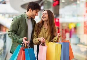 Joyful Couple On Shopping Laughing Holding Colorful Shopper Bags Buying New Clothes In Modern Hypermarket On Weekend. Happy Customers Spending Weekend In Mall. Great Sales Concept photo