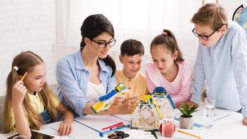 Little technicians working together with teacher in robotics class, creating diy robot photo