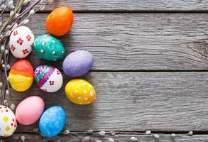 Handmade painted easter eggs on wood background. Colorful holiday decoration on rustic table top view with copy space photo