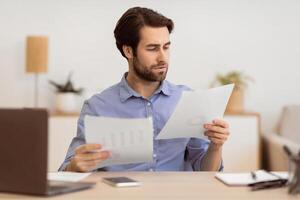 Serious Businessman Entrepreneur Looking Through Documents And Papers Reading Business Correspondence, Reports And Financial Bills Working Sitting In Modern Office. Selective Focus photo