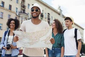 Travel together. Happy hipsters using navigation map to explore the city photo