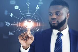 Analytics and monitoring of world economics and business management. Serious african american man with beard clicks on virtual planet button on digital screen with icons, double exposure, collage photo