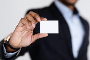 Selective focus on blank card in african american businessman hands, unrecognizable manager representing himself with empty business card, copy space, studio or office wall background photo