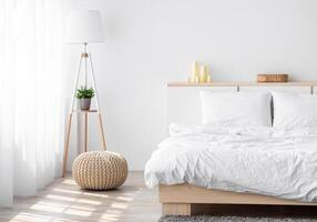 Soft double bed, lamp with plant, furniture with accessories, window with curtains on white wall background, empty space. Cozy apartment in Scandinavian style, minimalist bedroom in morning at home photo