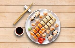 Japanese food restaurant, sushi maki gunkan roll plate or platter set. Set for two with chopsticks, ginger, soy, wasabi. Sushi at wooden planks background. Top view, flat lay. photo