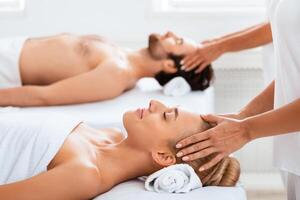 Relaxed Spouses Getting Acupressure Head Massage Together Relaxing Lying On Beds At Spa Salon Indoor, With Eyes Closed. Wellness, Relaxation, Beauty Day For Couple Concept. Selective Focus photo