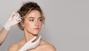 Young beautiful woman getting botox injection for eyes area, standing over grey studio background, panorama with copy space, banner photo