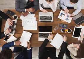 Diverse business team at meeting, discussing marketing strategy and working on gadgets, top view photo