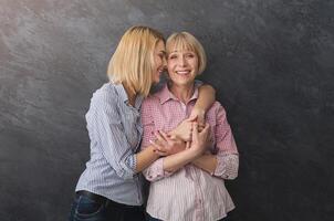 Happy adult mother and daughter embracing, spending time together on grey background. Generation and relationship concept photo