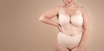 Self Acceptance. Beautiful Curvy Lady In Underwear Posing On Beige Background In Studio, Body Positive Plus Size Woman In Lingerie Enjoying Her Natural Beauty, Cropped Image With Copy Space photo