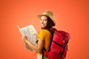 Smiling young woman tourist with backpack holding city map, yellow studio background. Cheerful lady holding map, looking over shoulder, impressed by great travelling opportunities, copy space photo