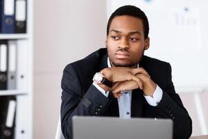 Upset african american businessman working with laptop in office, looking at copy space, suffering from problems with business. Crisis in business, financial difficulties, burnout at job concept photo