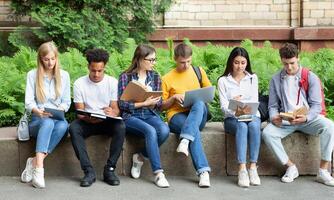 Students preparing for lecture. Teens sitting in university campus with books and devices photo