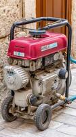 A small red and white gas powered engine sitting on the ground photo