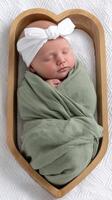 A newborn girl in a green wrap in a wooden box photo