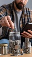 Man putting coins in a jar with a digital tablet photo