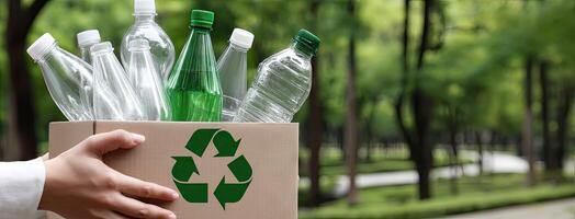 A person is holding a cardboard box with several plastic bottles photo