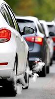 Cars are driving down the road with smoke coming out of the tailpipe photo