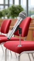 A microphone is sitting on a chair in front of red chairs photo