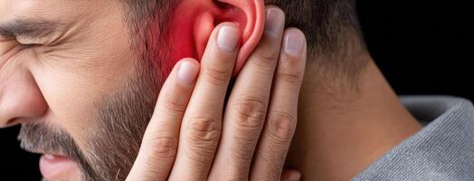 A man with a red ear is holding his ear photo