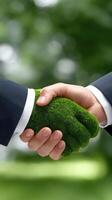 Businessman shaking hands with green grass on background stock photo