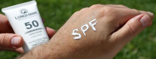 A person holding a tube of sunscreen on their hand photo