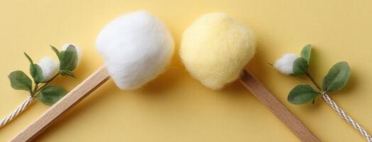 Two cotton balls and wooden spoons on a yellow background photo
