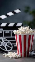 A bucket of popcorn and a movie clapper on a table photo
