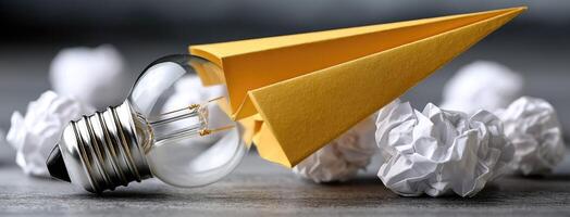 A yellow paper airplane with a light bulb on top photo