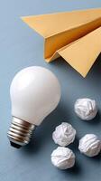 A light bulb, paper airplane and crumpled paper photo