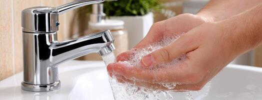A person washing their hands with soap and water photo