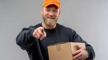 A man with a beard and a cap holding a box photo