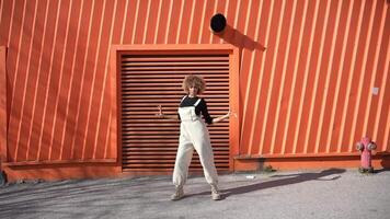A Modern Dancer is Posing Gracefully Against a Bright and Vibrant Orange Wall Background video