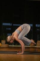 Dynamic yoga practice showcasing a woman performing an advanced pose in a serene and well-lit indoor studio environment during a peaceful evening session photo
