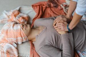 Man lying on the floor while a person ties a cloth around his eyes during a relaxation or meditation practice in a serene indoor setting... photo