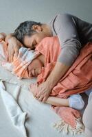 Couple embracing each other intimately while bundled in cozy blankets on a soft floor during a serene moment at home in the afternoon photo