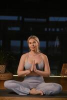 Woman practicing yoga in a modern studio with soft lighting while sitting in a meditative pose and hands in prayer position photo
