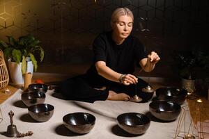 Practicing sound therapy with singing bowls in a serene indoor space at dusk for relaxation and meditation purposes photo