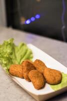 Crispy golden nuggets served on fresh lettuce with soft ambient lighting in the background captures the delicious essence of comfort food at a casual dining setting. photo