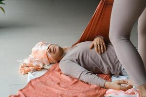 Individual receiving gentle support during a wellness session in a tranquil indoor setting with calming colors and natural light in the early afternoon.. photo